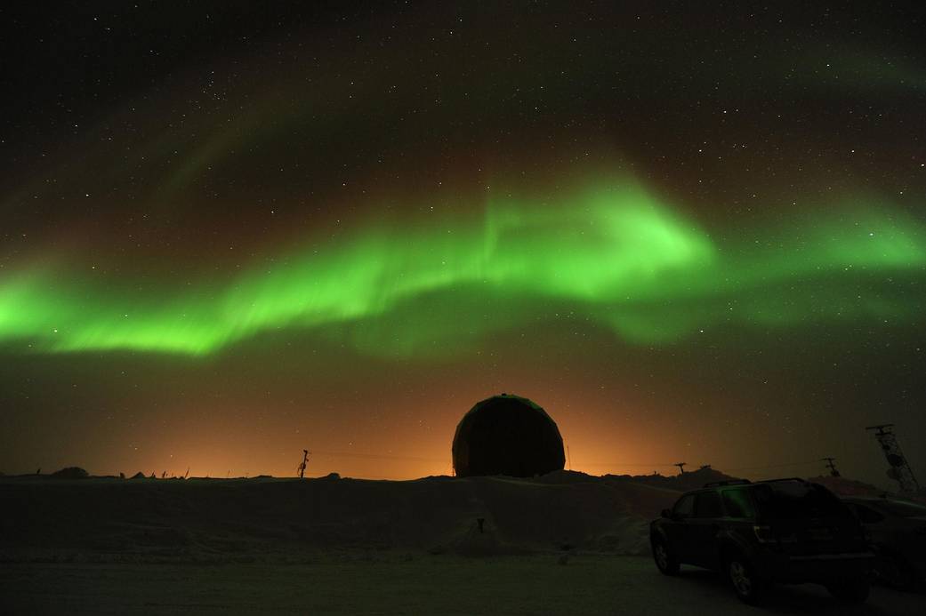 A green band of aurora above a snowy research site at Poker Flat, Alaska, photographed by James Spann.