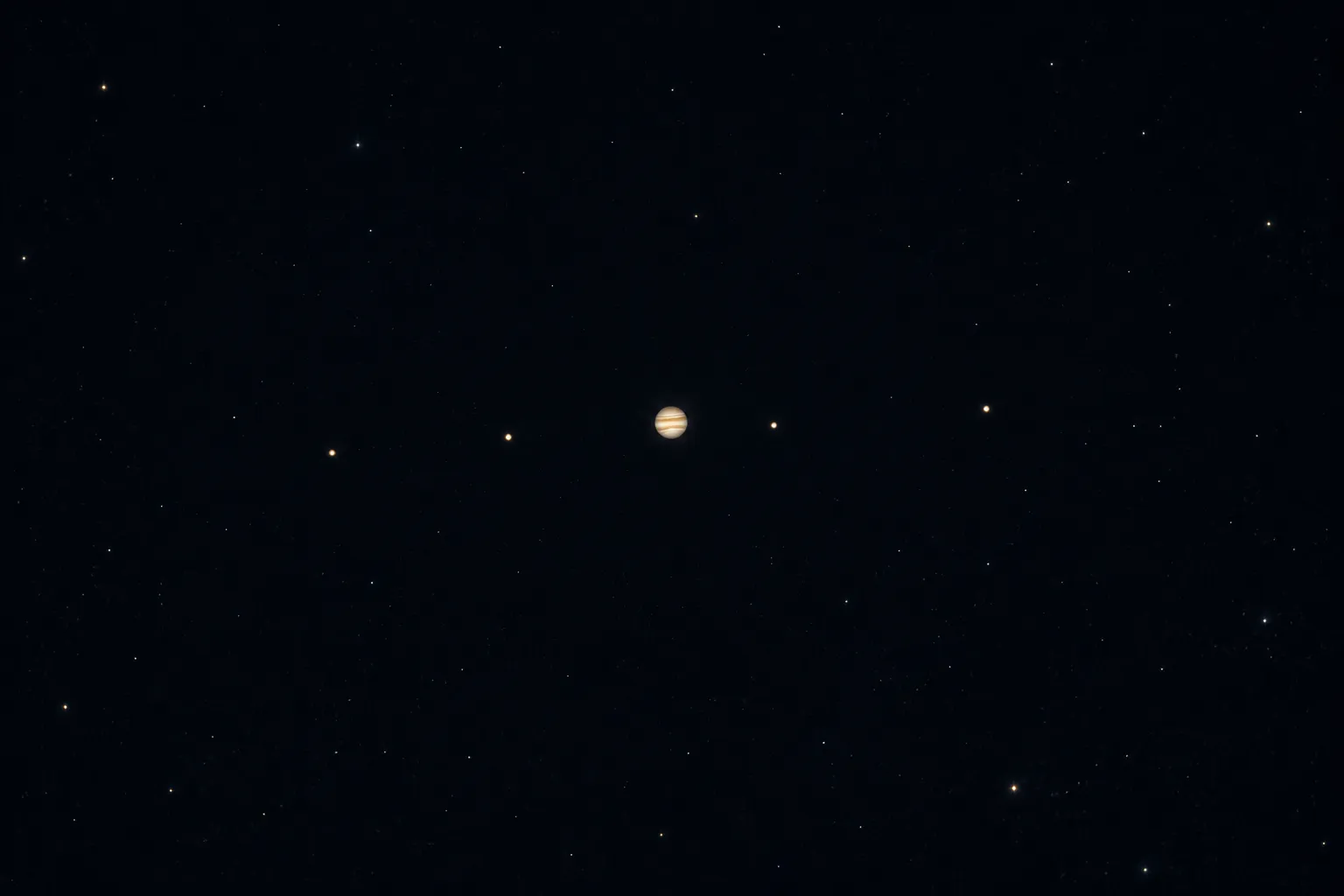 Jupiter as a bright point with four smaller points strung in a line beside it.