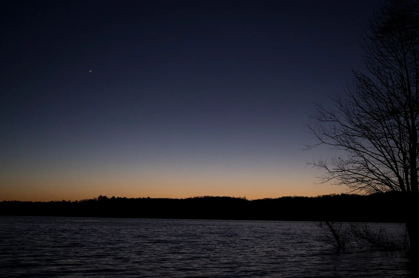 Jupiter and Saturn as two bright points in a twilight sky above a lake.