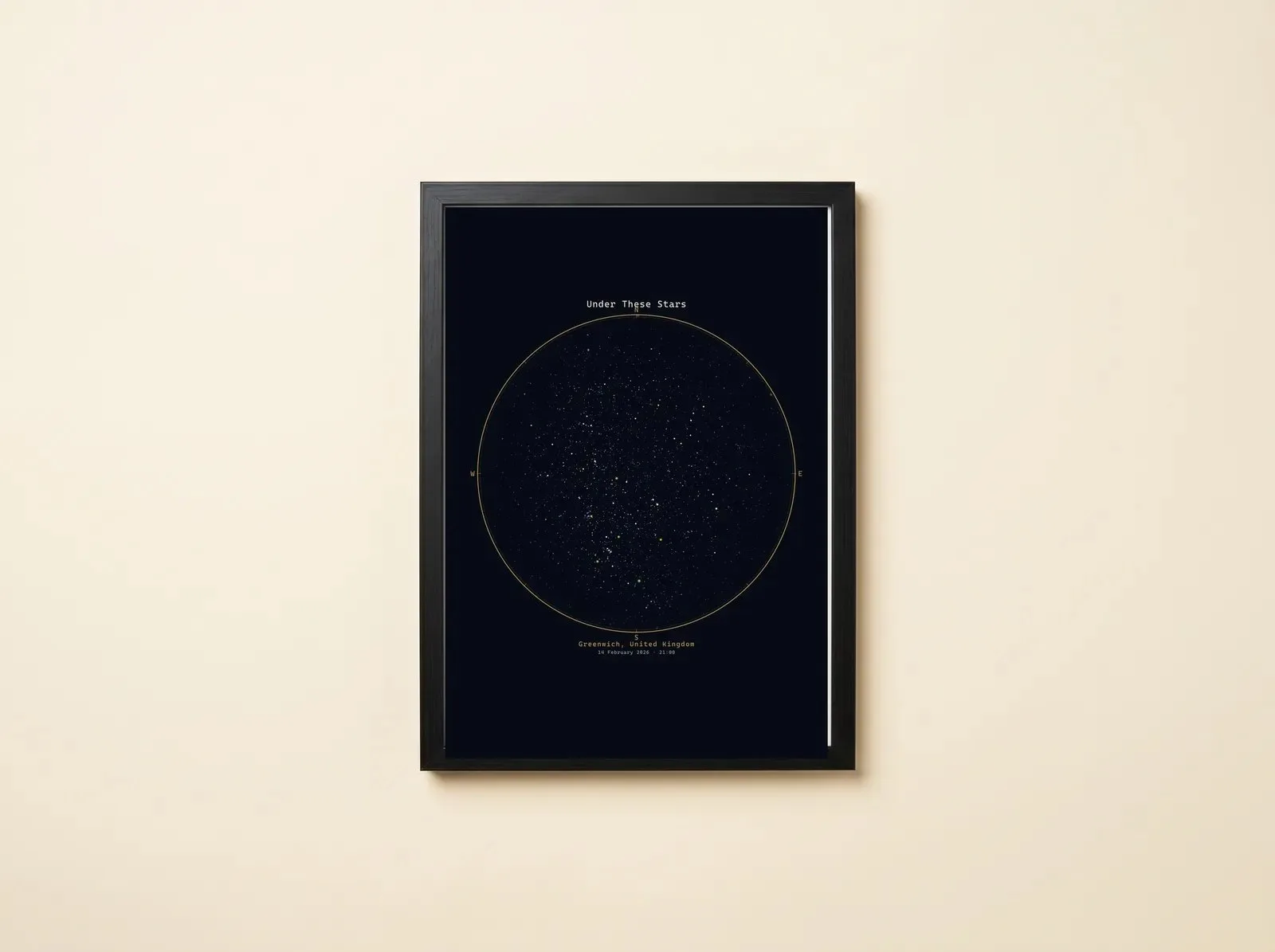 A black-framed star map on a pale wall: a circular field of stars inside a fine gold rule, a title above it and the place and date printed beneath.