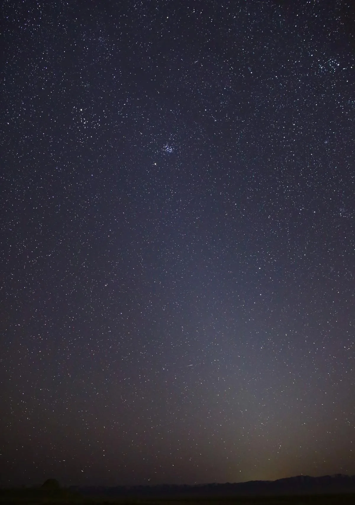 The zodiacal light, a faint cone of sunlight scattered by dust along the zodiac, rising above a dark desert horizon.