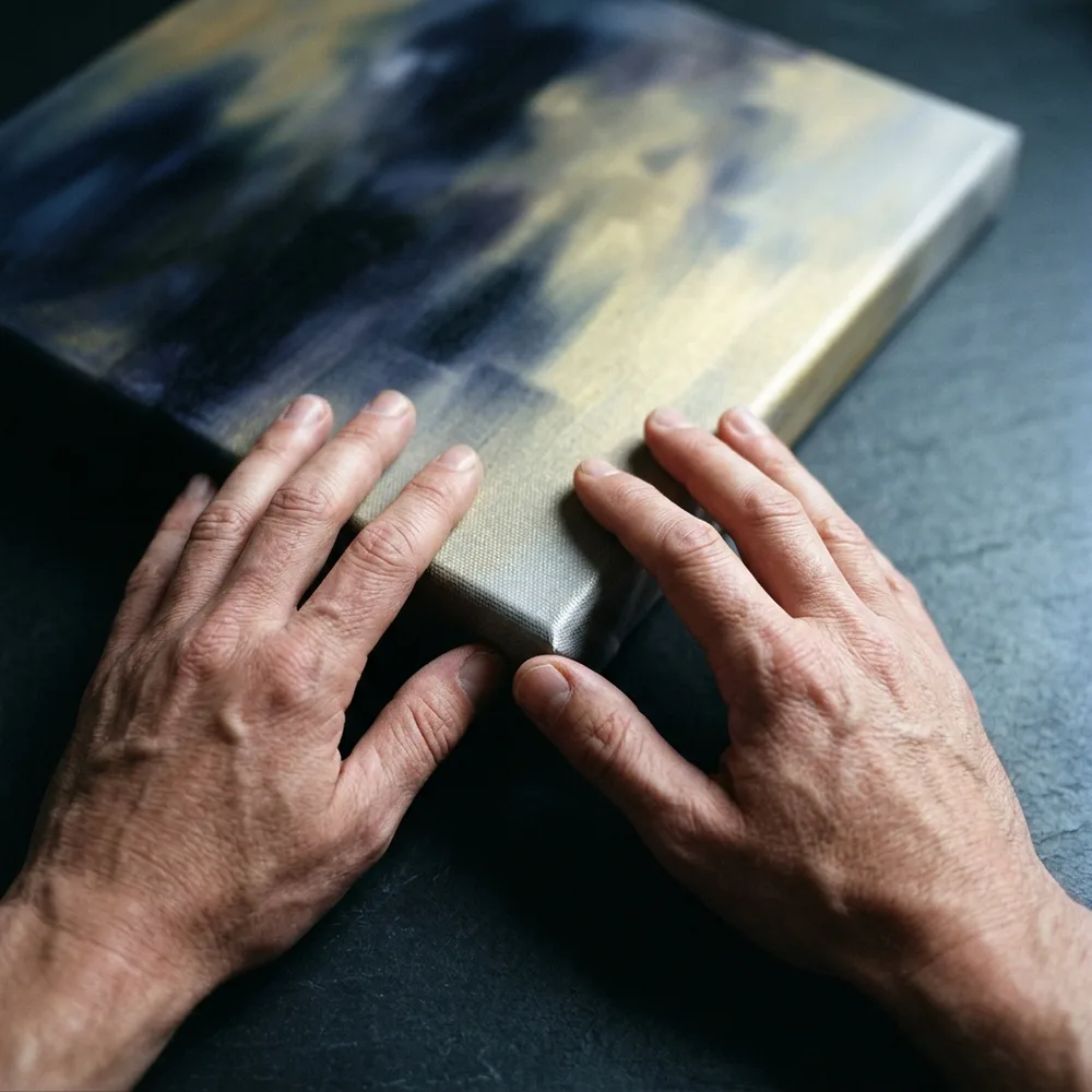 A pair of hands on the wrapped edge of a canvas
