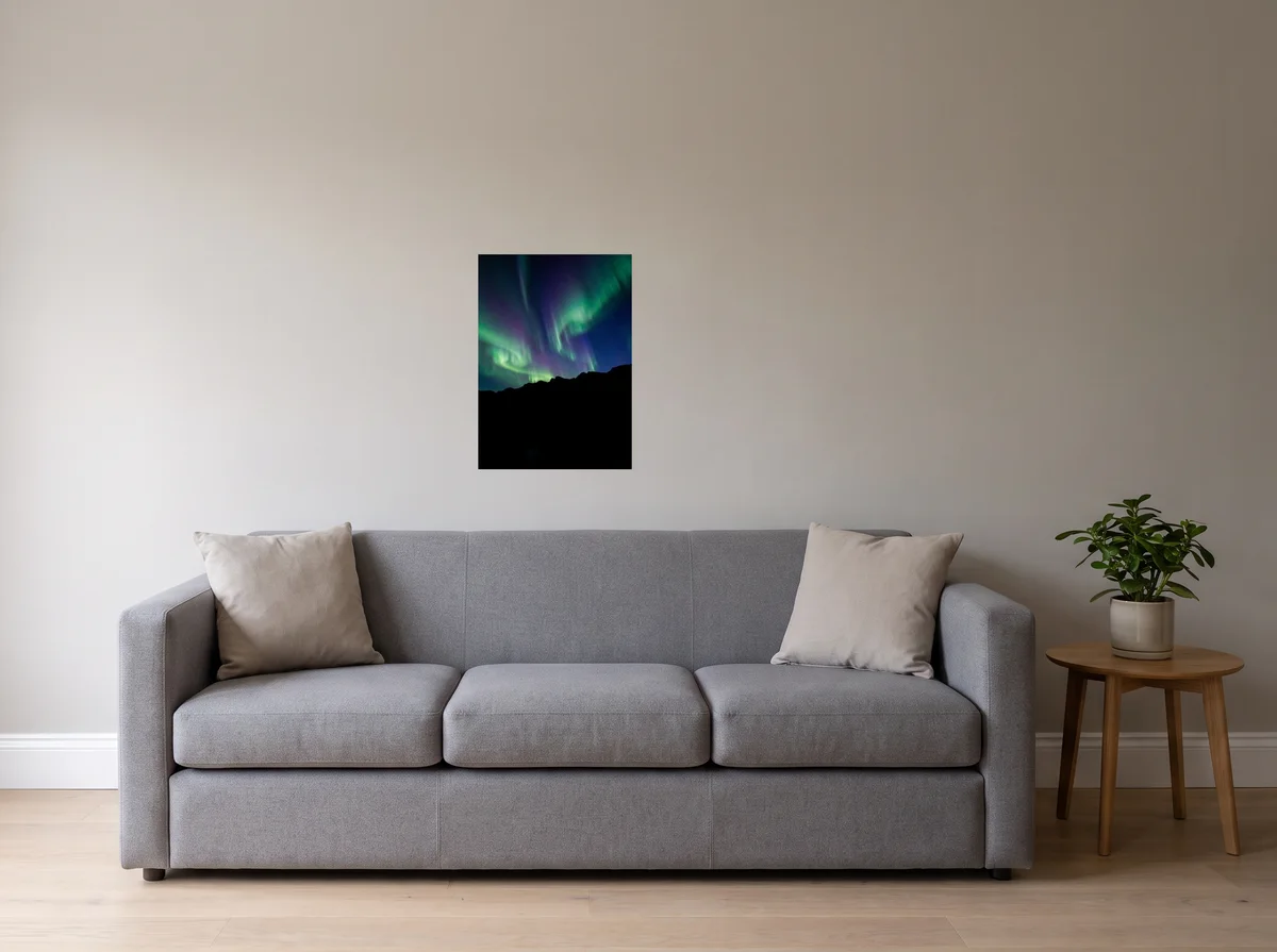 Aurora as a 50x70 cm poster on a light grey wall above a grey sofa