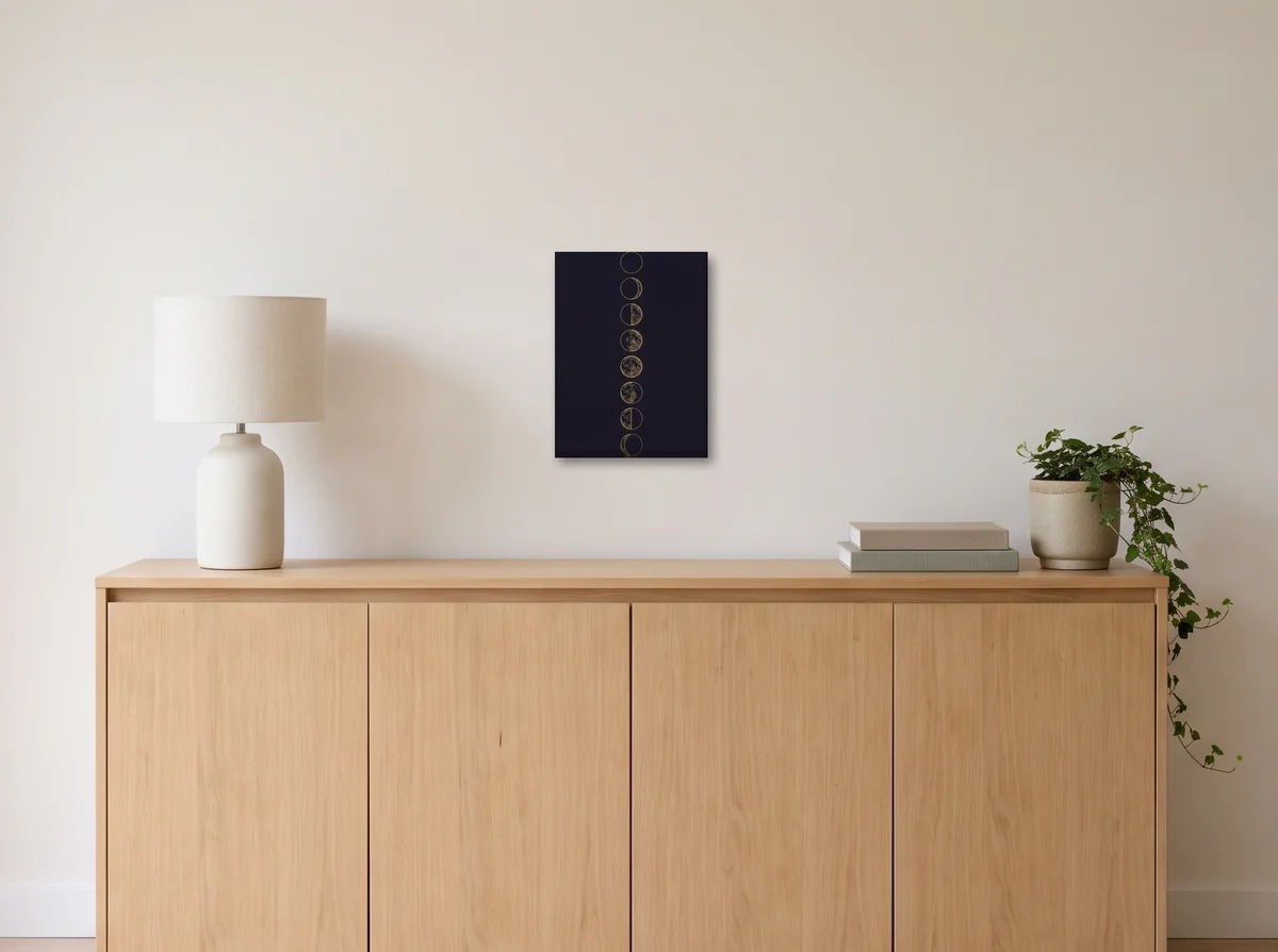 Lunar Phases as a 30x40 cm canvas on an off-white wall above an oak sideboard with a lamp and plant