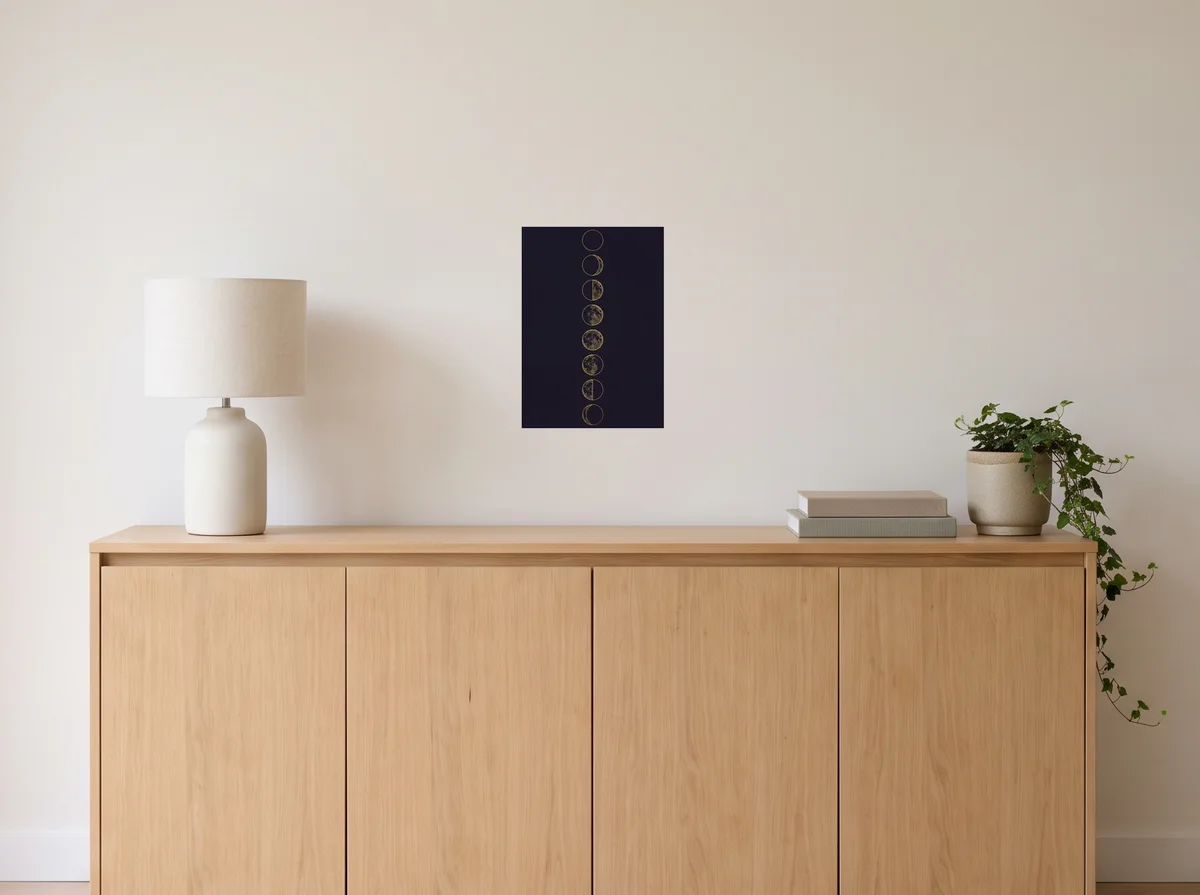 Lunar Phases as an A3 poster on an off-white wall above an oak sideboard with a lamp and plant
