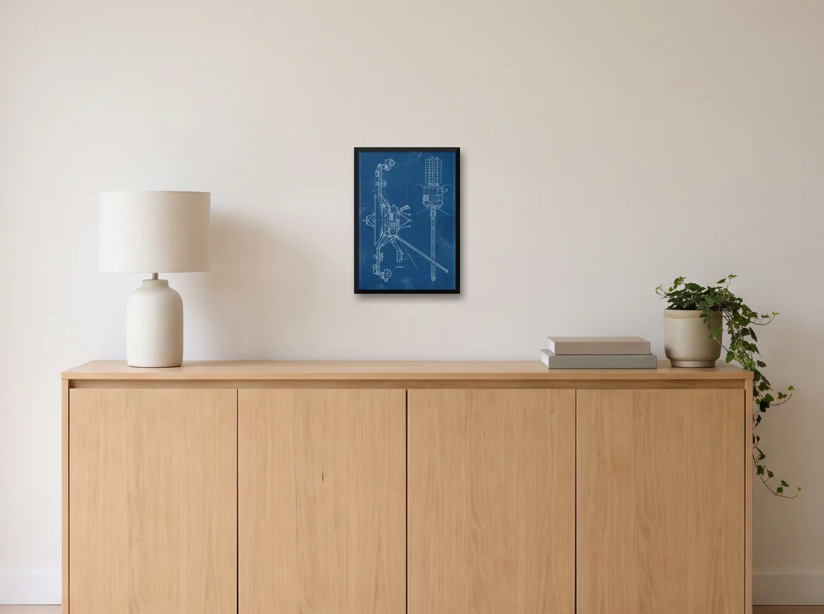Voyager Blueprint as an A3 poster in a black frame on an off-white wall above an oak sideboard with a lamp and plant.