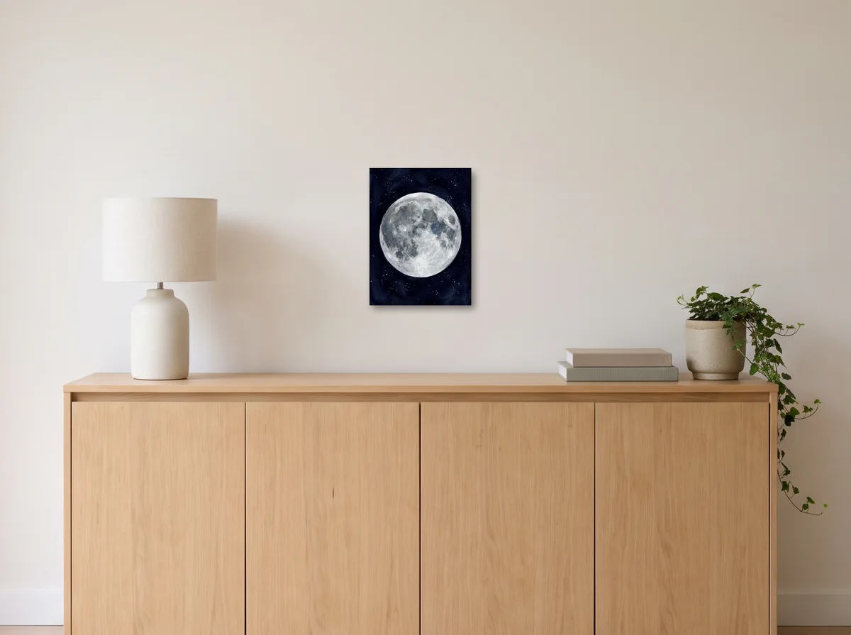 Watercolour Moon as a 30x40 cm canvas on an off-white wall above an oak sideboard with a lamp and plant